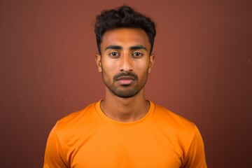 Fototapeta premium Portrait of a content indian man in his 20s sporting a breathable mesh jersey in front of blank studio backdrop