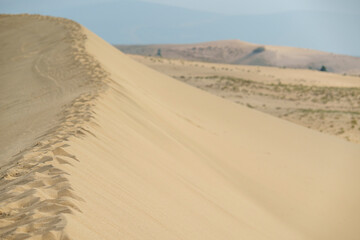 Golden desert dunes illuminated by sunbeams under a dramatic sky