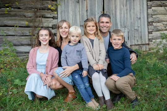 Portrait of a family sitting in front of a wooden building in Beckwith Township at Carleton Place in the Ottawa Valley; Ontario, Canada