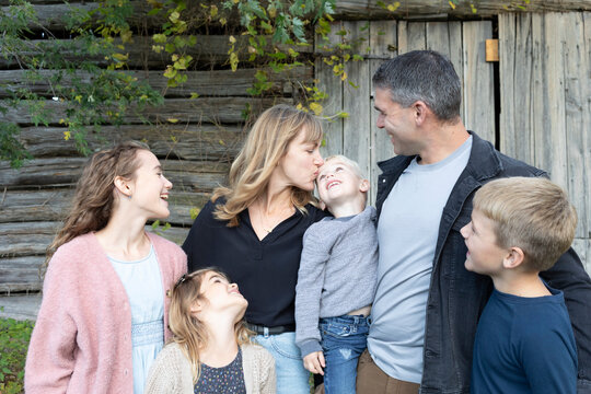 Portrait of a family in front of a wooden building, laughing and showing affection for each other, Beckwith Township at Carleton Place in the Ottawa Valley; Ontario, Canada