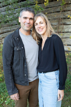 Portrait of a married couple smiling and standing in front of a wooden building in Beckwith Township at Carleton Place in the Ottawa Valley; Ontario, Canada
