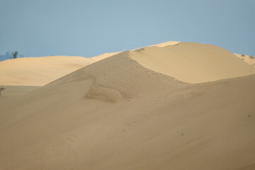 Golden desert dunes illuminated by sunbeams under a dramatic sky