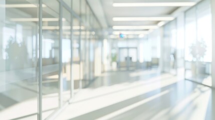 Fototapeta premium Blurred office interior background. Empty light open space office with big windows, many glasses walls, desks, chairs and green plants. Modern indoor business environment