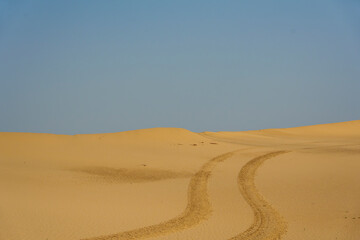 Golden desert dunes illuminated by sunbeams under a dramatic sky