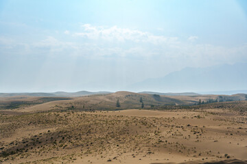 Golden desert dunes illuminated by sunbeams under a dramatic sky