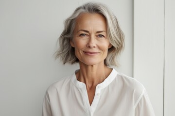 Fototapeta premium Portrait of a blissful woman in her 50s wearing a simple cotton shirt while standing against light wood minimalistic setup
