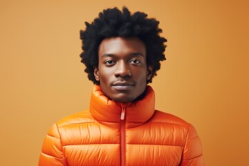 Obraz premium Portrait of a satisfied afro-american man in his 20s dressed in a thermal insulation vest while standing against light wood minimalistic setup