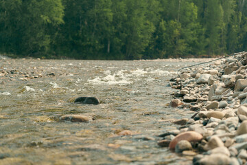Shallow river with rocky bottom flowing under bridge on a sunny day