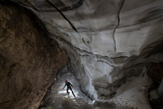 Caver rappels in the ice caves of the European Alps, threatened by global warming