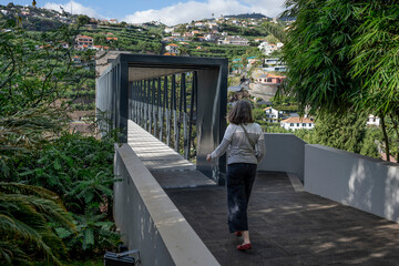 Woman walks towards an elevated walkway in the town of Ponta do Sol on the island of Madeira in Portugal; Ponta do Sol, Madeira, Portugal