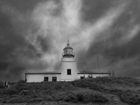 Black and white image of the low angle view of Ponta do Pargo lighthouse under a sky with clouds; Ponto do Pargo, Madeira, Portugal