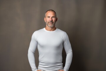 Obraz premium Portrait of a glad man in his 40s showing off a lightweight base layer in front of plain cyclorama studio wall