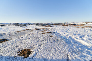 Snow melting on a vast frozen landscape under a blue sky