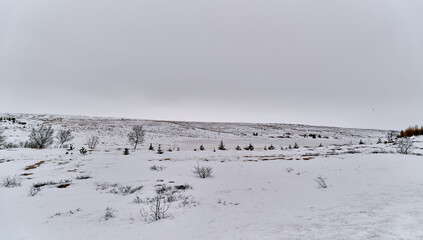 Frozen lake surrounded by snow covered hills on a cloudy winter day