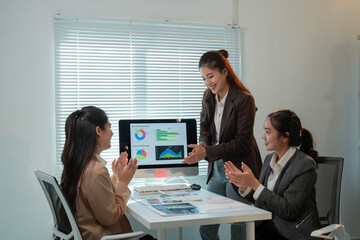 Asian businesswomen clapping their hands together after a successful presentation of the financial report on the computer screen in the office meeting room