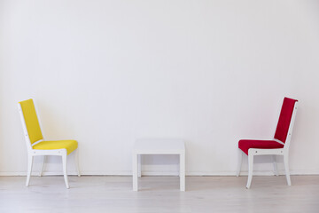 Two vintage yellow and red chairs with table in the interior of an empty white room