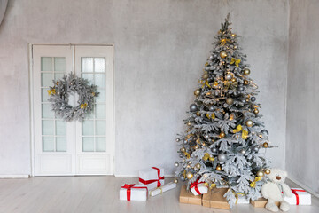 Snow-covered Christmas tree decorated with toys and gifts in the interior for the new year
