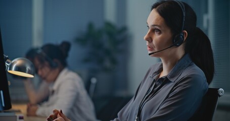 Multiethnic team of helpline operators working in call center of psychological hotline: Caucasian female specialist in headset communicating and supporting person on call. Suicide prevention service.