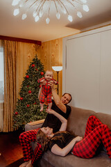 Family at Christmas in red pajamas having fun at home on the sofa