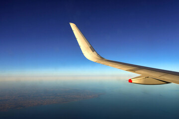 Wing and curved wingtip of a holiday jet in flight against a deep blue sky. Copy space.