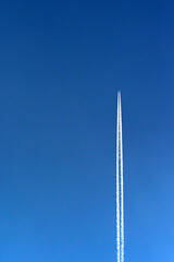 Holiday jet trailing white contrails across a deep blue sky. Travel concept.