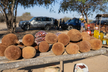 A variety of fresh baobab fruits are neatly arranged on a wooden stand for sale at a local market...