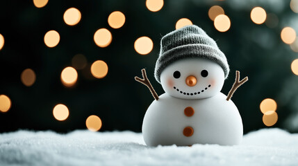 Obraz premium Cute snowman figure with a hat and stick arms standing on snow with blurred festive lights in the background.