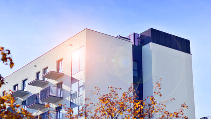 Modern high-rise apartment building  in white, stand tall against a blue sky, exemplifying...