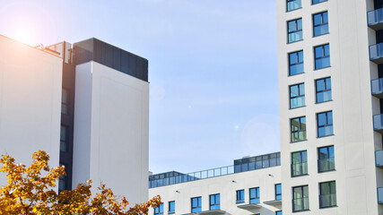 Modern high-rise apartment building  in white, stand tall against a blue sky, exemplifying...
