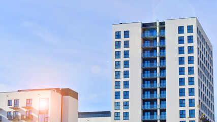 Modern high-rise apartment building  in white, stand tall against a blue sky, exemplifying...