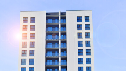 Modern high-rise apartment building  in white, stand tall against a blue sky, exemplifying...