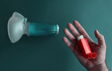 Anti-asthma inhaler on an open hand, in the background the image is completed with an inhaler chamber