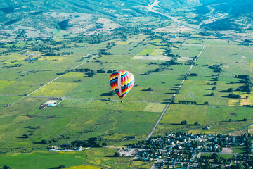 Aerial photo of a Beautiful, Colorful hot air balloon, flying above the vast green fields of Park City, Utah, USA