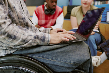 Group of students collaborating in inclusive classroom, with person in wheelchair using laptop for project. Diverse group engaged in learning activity without barriers