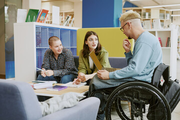 Group of students brainstorming ideas and discussing projects during study session in modern...