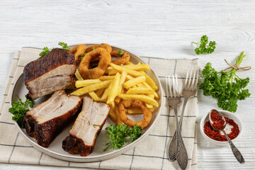 Baked pork ribs with onion rings and french fries