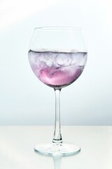 Lilac-Colored Cocktail with Ice Cubes on White Backdrop