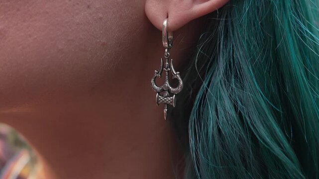 Young Woman With Trident of God Shiva Mahadev Trishula Jewelry Earrings. Craft divine Jewelry Details, Sterling silver, Design. Lady with blue dyed hairstyle. 
