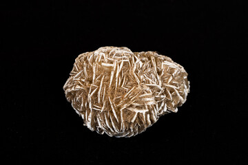 A rosette aggregate of gypsum and sand know as a desert rose on a black  background.