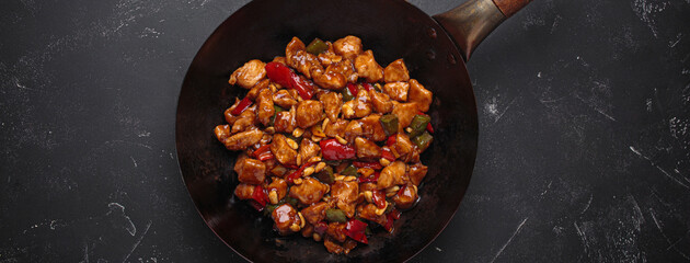 Wok is filled with savory kung pao chicken with tender chicken, crunchy peanuts and vibrant vegetables, all coated in a flavorful sauce