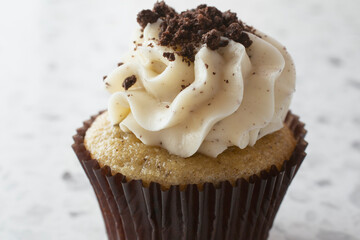 A closeup view of a vanilla cookies and cream cupcake.