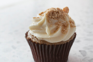 A closeup view of a vanilla cupcake, topped with cinnamon cereal.