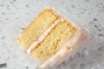 A view of a slice of strawberry vanilla cake in a plastic container.