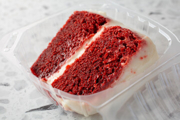 A view of a slice of red velvet cake in a plastic container.