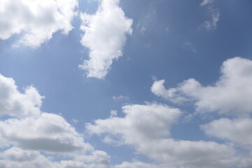 A bright blue sky is dotted with fluffy white clouds, drifting lazily across the expanse. The...