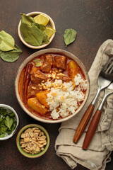Steaming bowl of massaman curry with beef, potatoes, and coconut milk sauce, served with rice and peanuts, a traditional flavorful thai meal