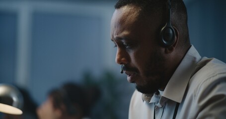 Call center office of psychological helpline: Close up portrait of African American male hotline operator talking on headset, consulting person online, providing mental health help. Emotional support.