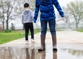 two boys splashing in rain puddles
