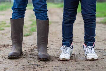 two kids legs standing in the mud