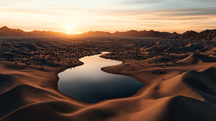 Desert landscape at sunset with sand dunes and a narrow reflective waterbody surrounded by sparse vegetation and distant mountains under a colorful sky.